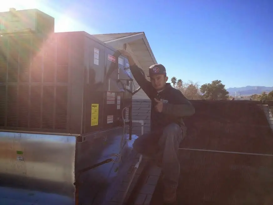 HVAC technician performing Air Duct Repair on a rooftop unit in Ionia